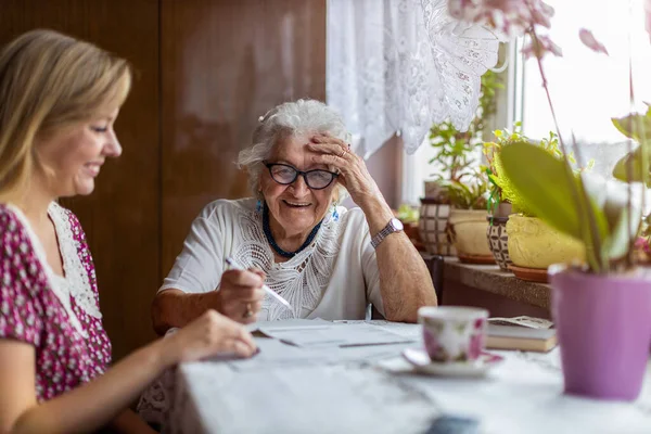 年轻妇女在家里与年迈的祖母呆在一起 — 图库照片