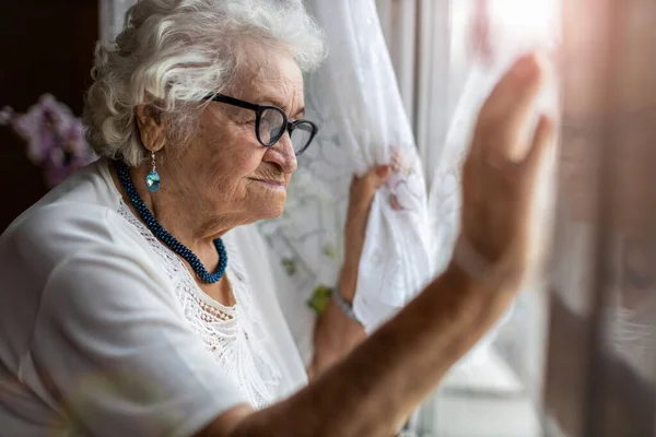 Oudere Vrouw Die Thuis Uit Het Raam Kijkt — Stockfoto