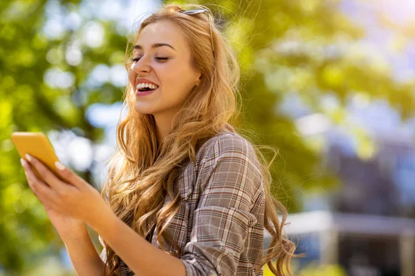 快乐的年轻女人在城市里用智能手机 — 图库照片