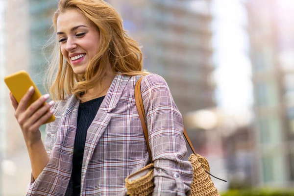 市内でスマートフォンを使う幸せな若い女性 — ストック写真