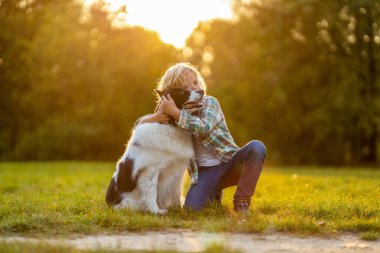 Küçük çocuk parkta köpeğiyle oynuyor.