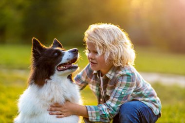 Küçük çocuk parkta köpeğiyle oynuyor.
