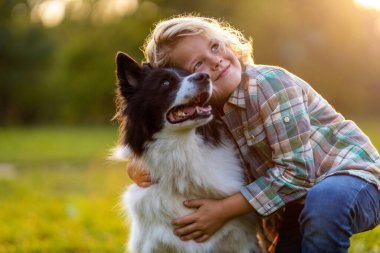 Küçük çocuk parkta köpeğiyle oynuyor.