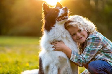 Küçük çocuk parkta köpeğiyle oynuyor.