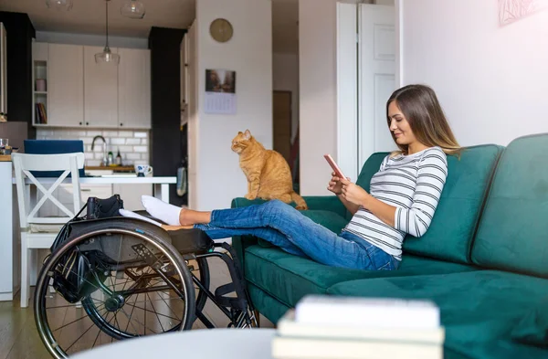 Evde Kanepede Otururken Akıllı Telefon Kullanan Engelli Genç Bir Kadın — Stok fotoğraf