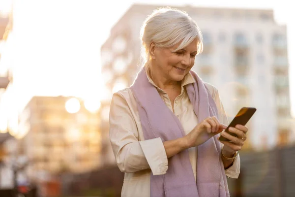 Старша Жінка Використовуючи Мобільний Телефон Свіжому Повітрі Під Час Заходу — стокове фото