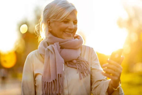 Senior Kvinna Använder Mobiltelefon Utomhus Vid Solnedgången — Stockfoto