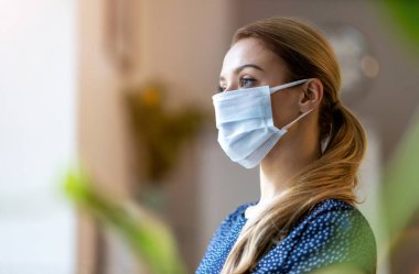 COVID-19 sırasında güvenlik ve koruma için ofiste koruyucu yüz maskesi takan bir kadın.