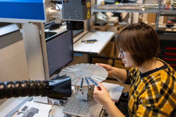 Woman operating a machine that prints logos on pens