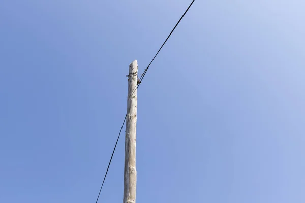 Postes y líneas eléctricas contra un cielo azul — Foto de Stock