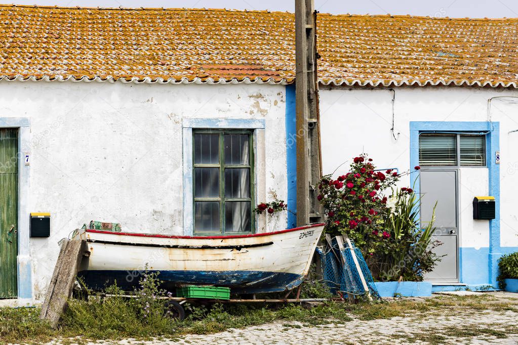 Old fishing boat in front of a Portuguese house