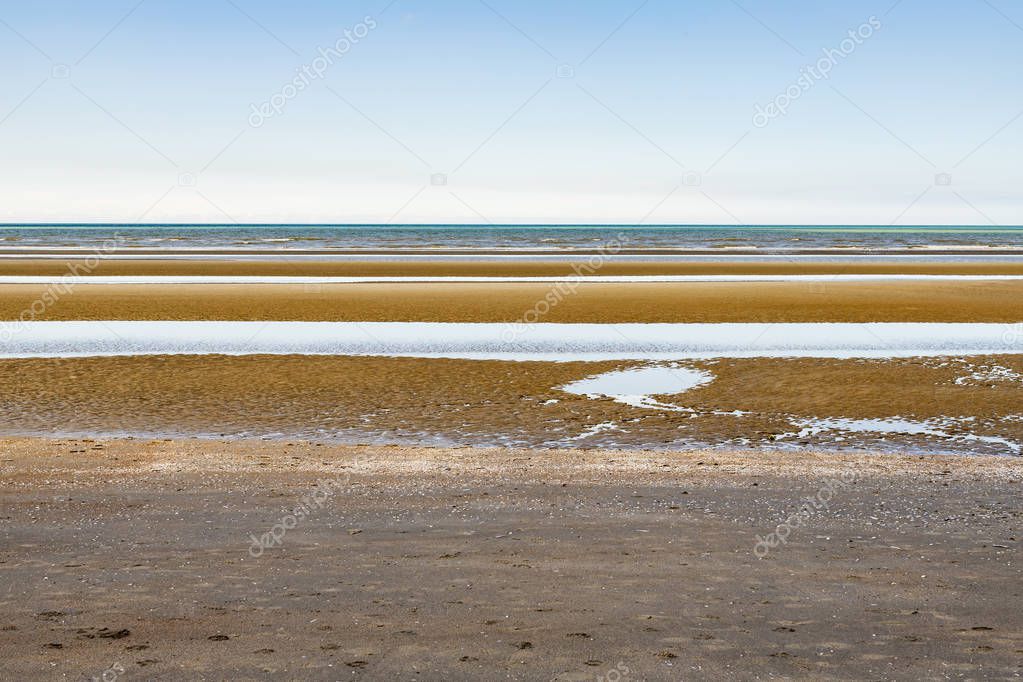 Oostduinkerke, Belgium - June 19, 2019: Layered minimalistic seascape with blue, green and orange tints