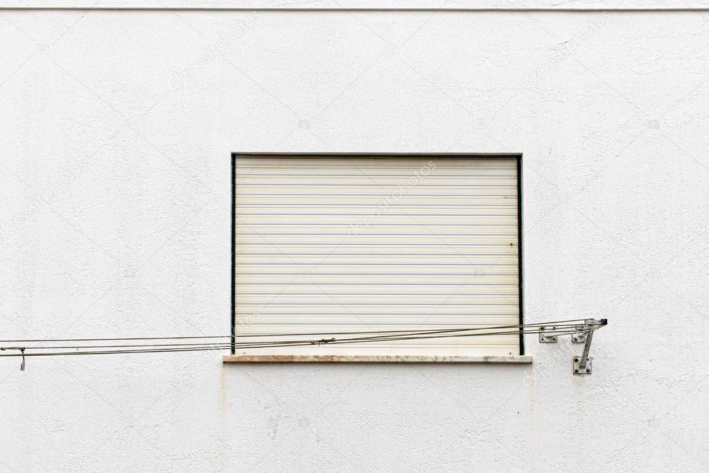 Nazare, Portugal - July 17, 2019: Weathered empty washing line in front of a white wall and window