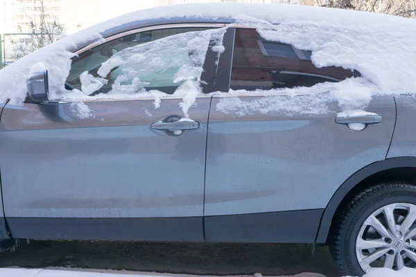 The car, covered with thick layer of snow. Negative consequence of heavy snowfalls. the left part of the car covered with snow