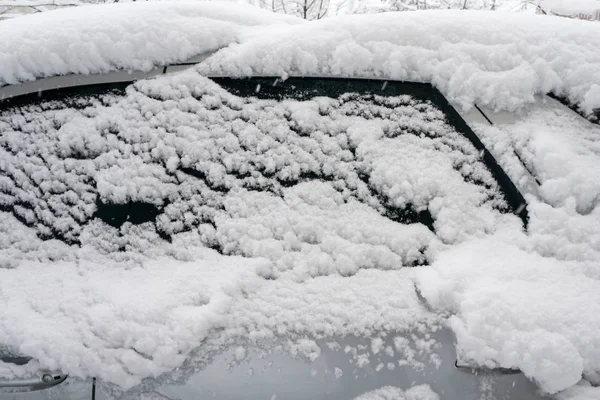 The car, covered with thick layer of snow. Negative consequence of heavy snowfalls. the left part of the car covered with snow
