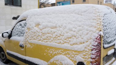 Araba kompakt sarı van kaplı kar kış gününde donmuş. Şehir hayatının kış döneminde kar fırtınası içinde kentsel sahne