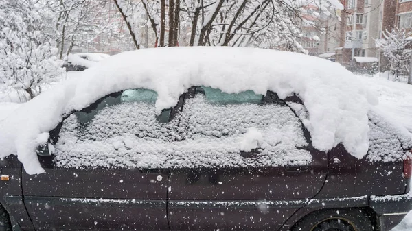 The car, covered with thick layer of snow. Negative consequence of heavy snowfalls. parked cars