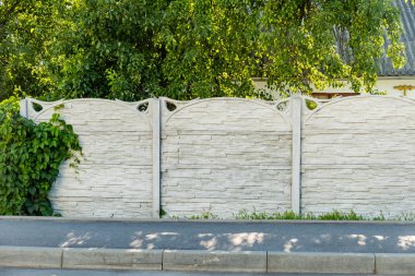 Dekoratif yeşilimsi gri beton bloklardan yapılmış bir çit.