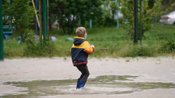 Маленький Хлопчик Медичній Масці Гумові Чоботи Стрибає Калюжі Танцює Весняний — стокове відео