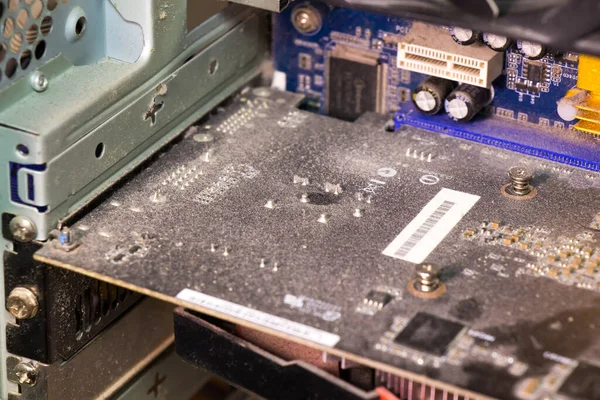 the computer video card in dust, close up, against a dark background, a board.