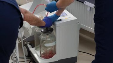 Bir hemşire ve bir asistan ameliyathanede kan akıtmak için vakum tüpleri hazırlıyorlar..