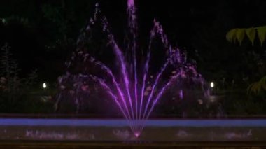 Geceleri küçük dekoratif çeşme. Çeşme farklı renklerde ışıklarla aydınlanır..