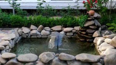 Taştan bir havuzda sürahide akan şelaleyle süslenmiş küçük bir mantar çeşmesi. Peyzaj tasarımı.