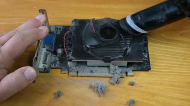 Usta, video kartındaki soğutucuyu elektrikli süpürgeyle temizliyor. Elle yakından çek. Bilgisayar ekipmanlarının onarımı ve önlenmesi.