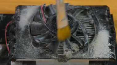Usta, video kartındaki soğutucuyu fırçayla temizliyor. Bilgisayar ekipmanlarının onarımı ve önlenmesi.