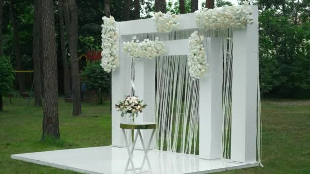 白い色の結婚式のための場所 森の中のパステルローズの花束と白い正方形の結婚式のアーチ — ストック動画