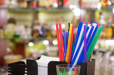 Bar tezgahında renkli pipetleri kapatın. Bulanık parlak arkaplan.