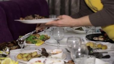 Garson yemek artıklarıyla birlikte kirli tabakları topluyor. Tatil sonrası masalar ya da ziyafet.
