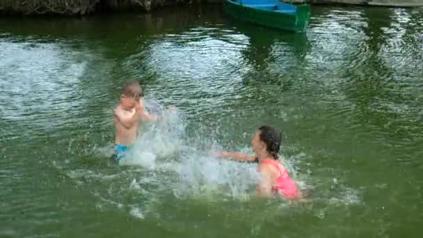 湖の上に小さな男の子と女の子の水しぶき 夏の屋外レクリエーション 幸せな子供時代の概念 スローモーション100 Fps — ストック動画