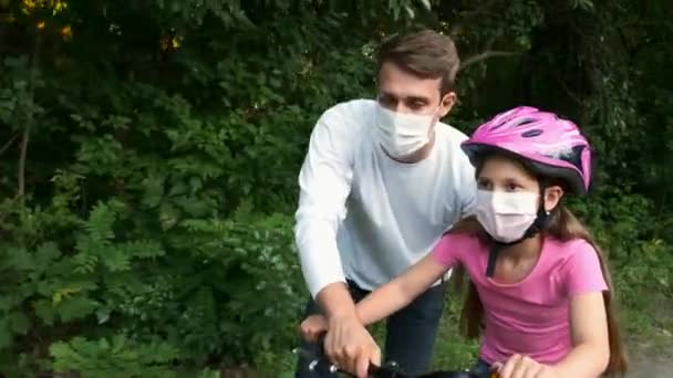 Padre Joven Enseña Hija Montar Bicicleta Con Máscaras Médicas Casco — Vídeos de Stock