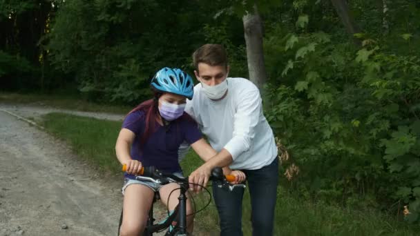 Padre Joven Enseña Hija Montar Bicicleta Con Máscaras Médicas Casco — Vídeos de Stock