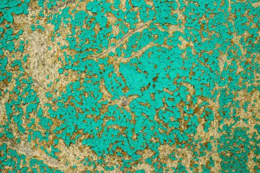 Ahşap bir duvarın eski yüzeyinin dokusu yeşil boyayla boyanmış, bir kat boya dökülmüş ve ağacın arkasına düşmüş.