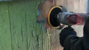 Yörünge zımpara makinesiyle eski ahşap bir yüzeyi öğüten bir adamın yakın çekimi. Eski bir evin yenilenmesi.