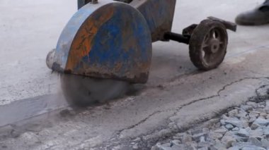 Dairesel testere ile asfalt elmas kesimi. İşçi asfaltın düzgün bir şekilde bağlanması için hat boyunca dikişleri kesiyor..