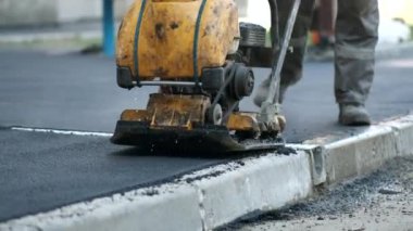 Yol vibroplakalı asfalt sıkıştırması. Yerleşim yerlerinin yakınındaki kaldırımlara kendi ellerinizle çarpıyorsunuz..