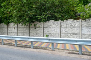 Yeşil ağaçların arka planında dekoratif beton çit.