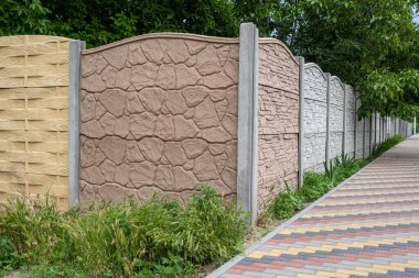 Bahçedeki yeşilliğin arka planına karşı çitin çok renkli beton levhaları.