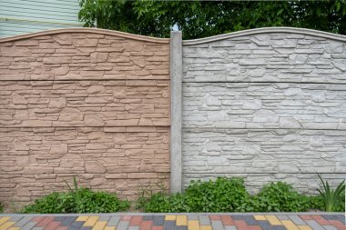 Bahçedeki yeşilliğin arka planına karşı çitin çok renkli beton levhaları.