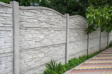 Yeşil ağaçların arka planında dekoratif beton çit.