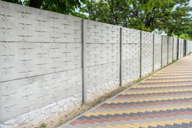Yeşil ağaçların arka planında dekoratif beton çit.