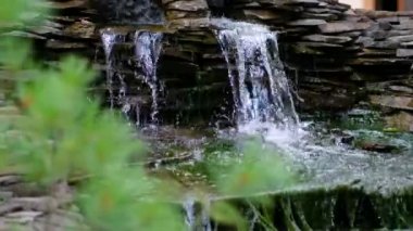 Bahçesinde şelale olan taş bir duvar. Granit taştan yapay dekoratif şelale. 