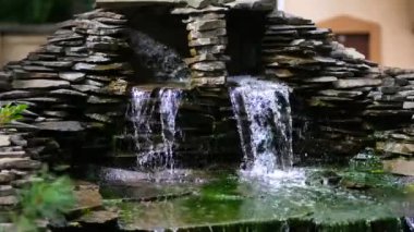 Bahçesinde şelale olan taş bir duvar. Granit taştan yapay dekoratif şelale. 