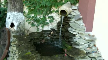 Taştan bir havuzda sürahide akan şelaleyle süslenmiş küçük bir mantar çeşmesi. Peyzaj tasarımı.