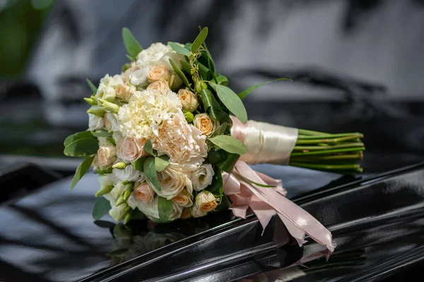 Mooie bruiloft boeket in roze tinten ligt op de motorkap van een zwarte bruiloft auto. bruiloft decor — Stockfoto