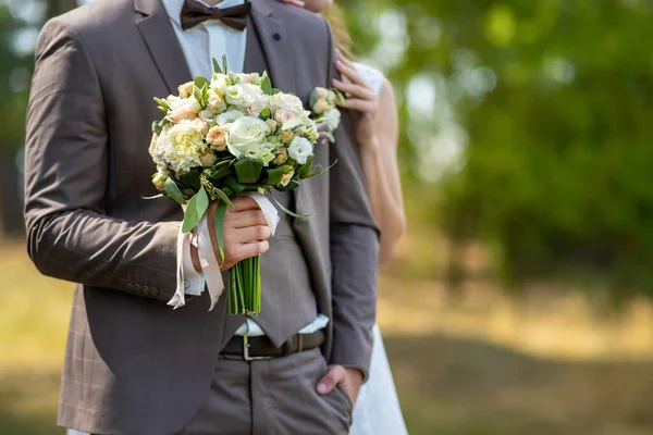 De bruidegom in een trouwpak heeft een prachtig boeket rozen in een roze tint — Stockfoto
