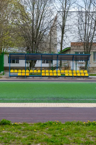 Yeşil çitin önündeki futbol sahasında spor bankında. — Stok fotoğraf